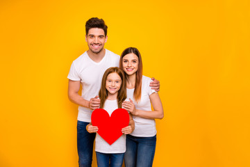 Portrait of three nice attractive charming lovely careful cheerful cheery tender amorous person holding in hands one big heart isolated over bright vivid shine yellow background