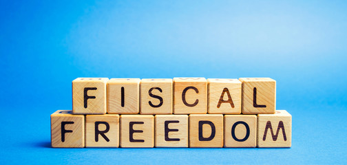 Wooden blocks with the word Fiscal freedom. Tax burden imposed by government. Taxation. Taxes concept. Business and Finance