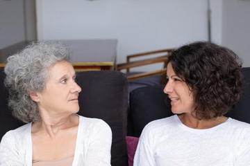 Mother and daughter looking at each other. Unhappy senior mother and middle aged daughter sitting on couch and having conflict. Family problem concept