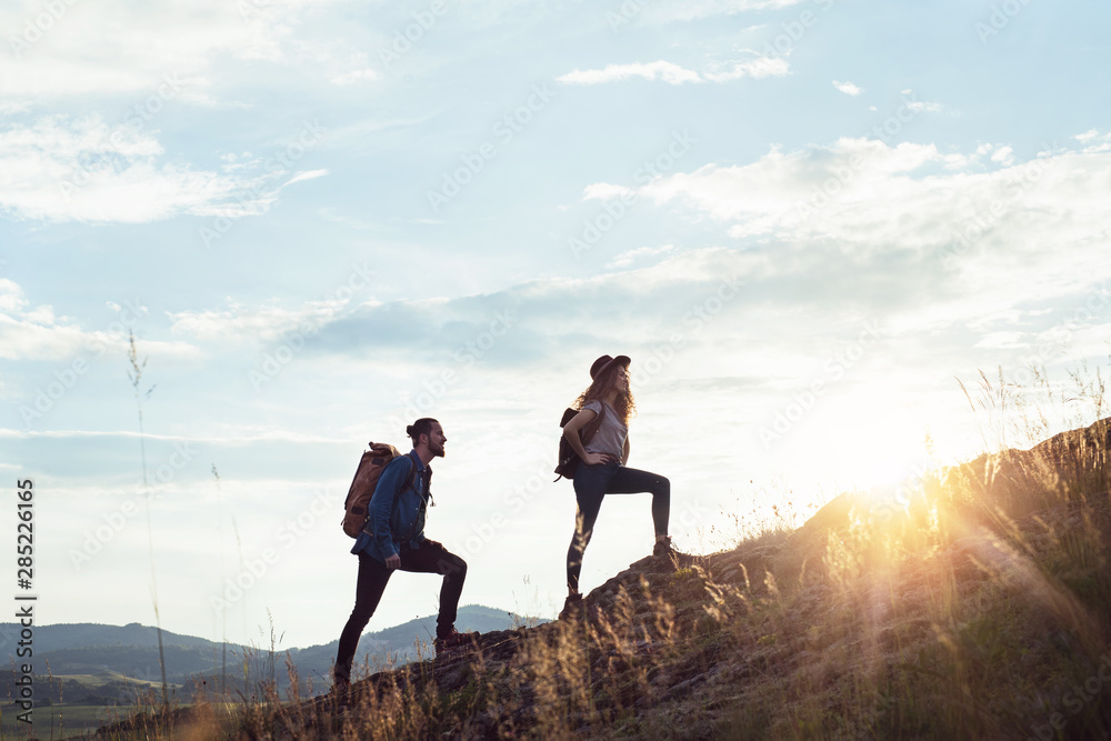 Wall mural young tourist couple travellers with backpacks hiking in nature.