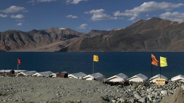 Colorful flags in front of white tents are blown by gusts of wind against the blue wetlands.