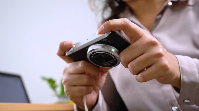 Back view of female photographer reviewing photos on her camera at office