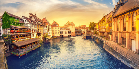 Colorful sunset in the region of Little France in the city of Strasbourg. Famous half-timbered houses, the river Ill and the bridge of St. Martin. Popular tourist destinations in Europe - obrazy, fototapety, plakaty