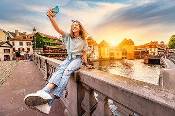 Happy and cheerful Asian girl traveler takes a selfie on the Saint Martin bridge in the Petit...