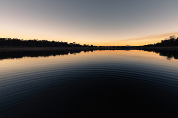 Fototapeta premium Reflection during winter sunset over dam on a clear day in Storm King, Queensland, Australia