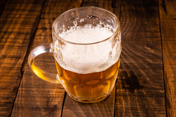 Very cold beer jug on a wooden table on a black background. Concept for the oktoberfest party.