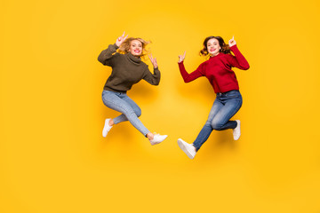 Fototapeta na wymiar Full length photo of cute ladies jumping high showing v-signs wear knitted pullovers isolated yellow background