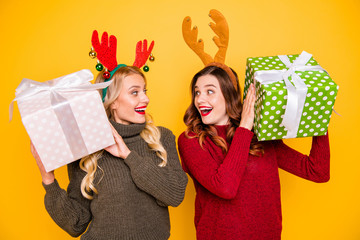 Photo of two amazed ladies received big giftboxes for xmas wear sweaters and head horns isolated...