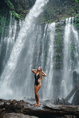Travel and freedom. Young girl travellr enjoy near big waterfall. Young woman backpacker looking at the waterfall in jungles. Ecotourism concept image travel girl