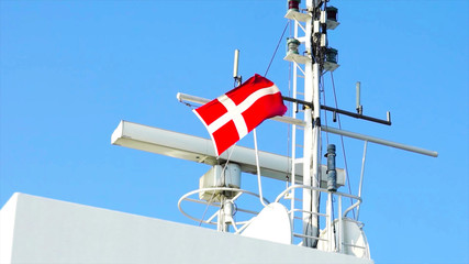 Danish flag on ship next to navigation and antenna and radar equipment