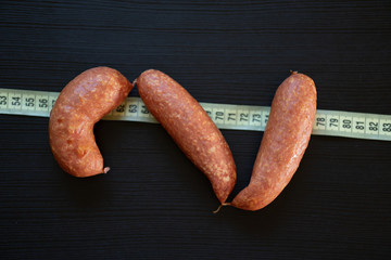 Diet concept - pork sausages wrapped with yellow measuring tape