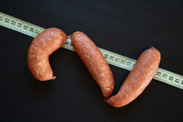 Diet concept - pork sausages wrapped with yellow measuring tape