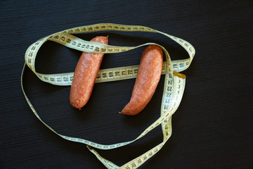 Diet concept - pork sausages wrapped with yellow measuring tape