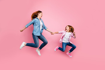 Full body photo of foxy little lady and her excited mom jumping high wear casual jeans outfit isolated pink background