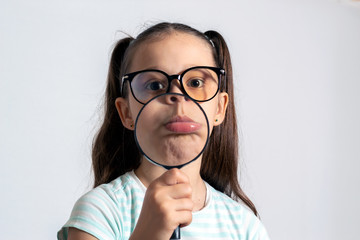 Little girl with a magnifying glass. The child looks like a sad monkey