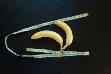 Diet concept - bananas wrapped with yellow measuring tape