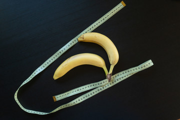 Diet concept - bananas wrapped with yellow measuring tape