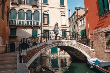 Fototapeta na wymiar Travel to Italy. Girl standing on the bridge in Venice. Beautiful well-dressed woman posing on a bridge over the canal in Venice, Italy. Europe travel vacation. Woman traveling to Venice