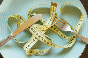 Diet concept - yelow measuring tape on plate.