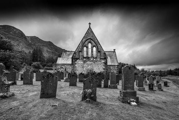 Church with gravestones with moody sky in black and white