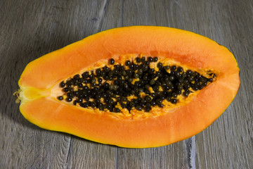 Fresh sliced papaya with seeds inside on a wooden background. Half of yellow papaya