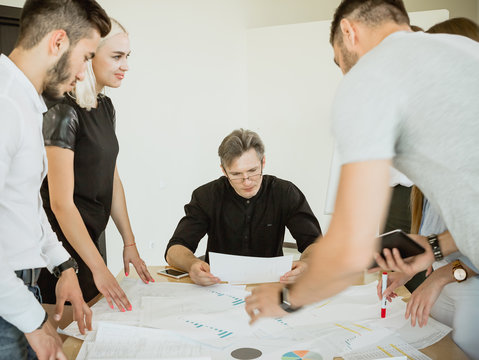 The company of young employees at a meeting with the project manager offer their options for project implementation