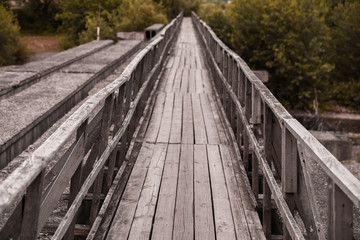 Fototapeta na wymiar Winding wooden bridge over a river old in deep forest, natural vintage background
