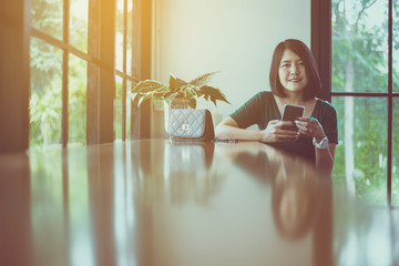 Beautiful asian woman using cell phone at cafe in the morning,Happy and smiling,Positive thinking