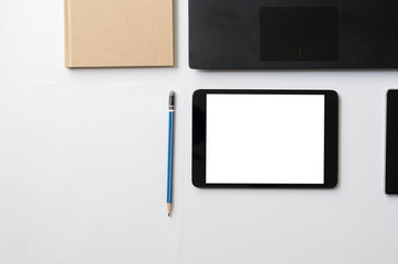 White Office desk with black laptop, black tablet, smartphone, book and blue pencil. Top view copy space. Business and education concept for work. It clean table