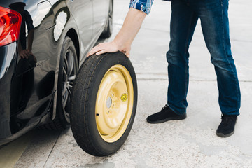 Man changing car tire with spare tire