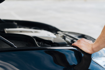 Naklejka premium Man leaning on car with open hood