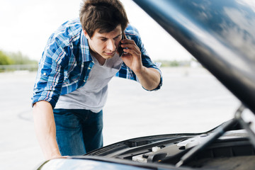 Man checking engine and talking on phone