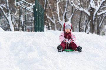 Fototapeta na wymiar kid slides down a hill on a sled