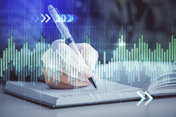 Double exposure of woman's hands making notes with forex graph hologram. Concept technical analysis.