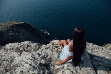 beautiful woman with long hair on a cliff ocean