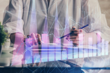 Financial forex graph drawn over hands taking notes background. Concept of research. Double exposure