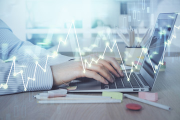 Double exposure of stock market graph with man working on laptop on background. Concept of financial analysis.