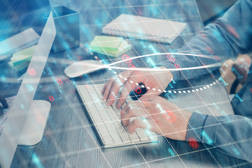 Double exposure of stock graph with businessman typing on computer in office on background. Concept...