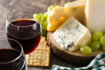 Assortment of cheeses and wine on wooden table. 