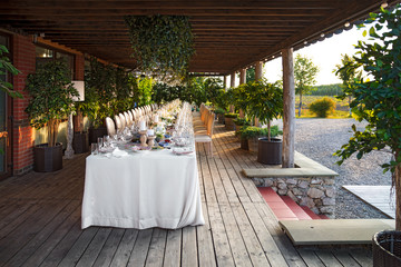 Outdoor wedding celebration at a restaurant. Festive table setting, catering. Wedding in rustic style in summer, beautiful small bouquets on a table.