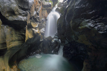 View of a waterfall in a deep narrow canyon known as Gouffre des Busserailles in Aosta valley near...