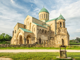 Traditional well and road in front of giant structure of Bagrati cathedral in Georgia. The church is one of the main attractions of Kutaisi, largest city of Imereti region.