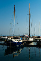 Fototapeta premium sailing boats with masts in sea dock reflecting in water