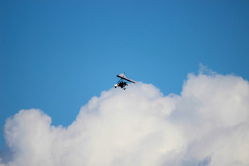 The hang-glider flying in the blue clear sky