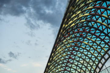 Bridge of Peace over Kura river in Tbilisi, Georgia, illuminated in evening. Closeup view of steel and glass construction against the sky. © dmitriygut