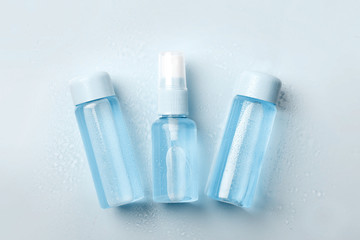 Three  bottles of tonic or lotion blue color and white towel on blue background. Freshness and body care. Female cosmetics. Micellar water. Travel set of face care cosmetic