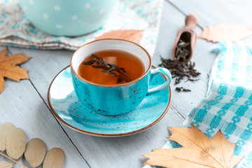 composition still life of a mug with hot leaf tea with berries and autumn leaves on a wooden surface