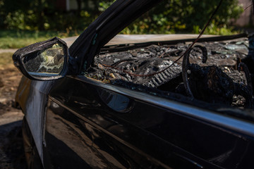 Car after the fire. Burned out car with an open hood. Arson, burnt car. Burnt interior trim, steering wheel, dashboard,