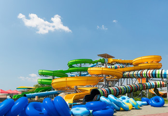 Water park, bright multi-colored slides with a pool. A water park without people on a summer day with a beautiful, cloudy blue sky