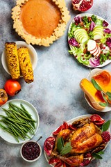 Thanksgiving dinner table with roasted whole chicken or turkey, green beans, mashed potatoes, cranberry sauce and grilled autumn vegetables. Top view, frame.